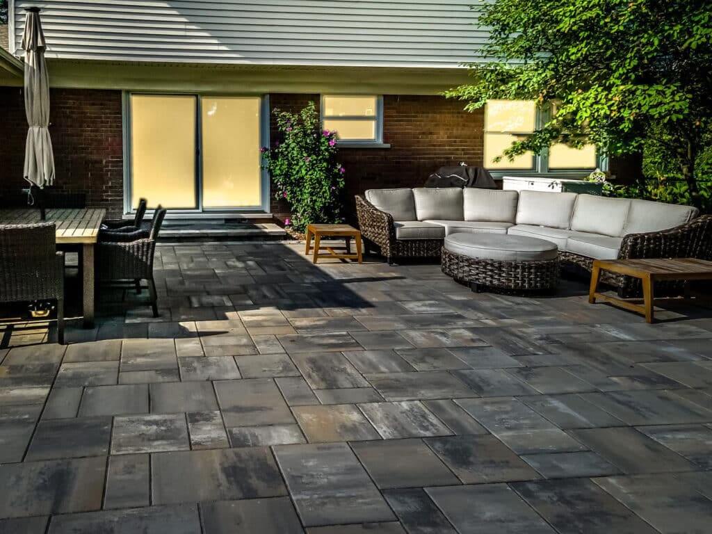 Michigan landscape design services, A stunning multi-zone backyard retreat featuring a custom stone patio, retaining walls, and expert planting layers meticulously executed by a professional Design & Build Landscaping company.