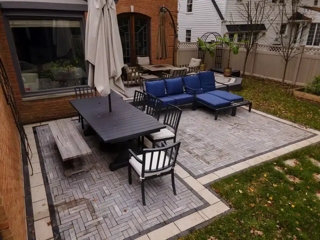 An elegant backyard living space featuring clean stone masonry, flawless modern paths, and pristine gardens seamlessly executed by a professional Design & Build team.