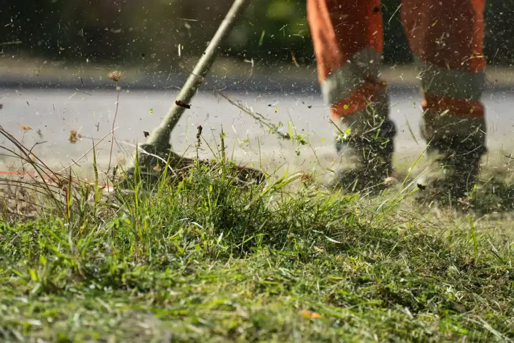 Professional landscaping service provider using a commercial lawn mower to cut grass on a residential lawn.